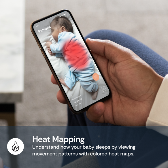 Hand holding a smartphone displaying a baby heat mapping app with a child's temperature indicated.