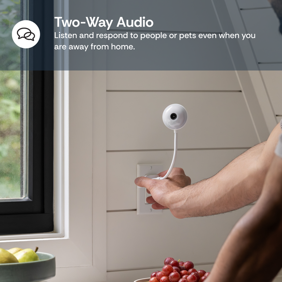 Person installing a smart home security camera on a wall next to a window.