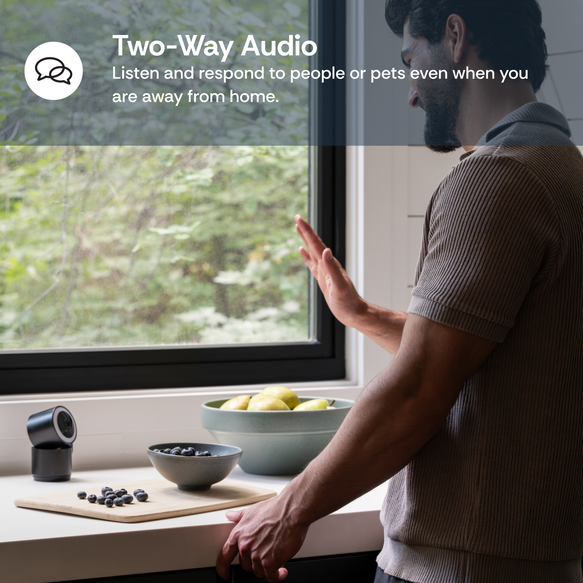 Person standing by a window with a device on a windowsill, promoting two-way audio functionality.
