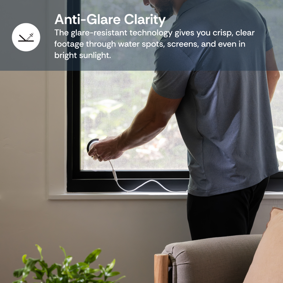 Person installing a camera on a window with text about anti-glare clarity technology.