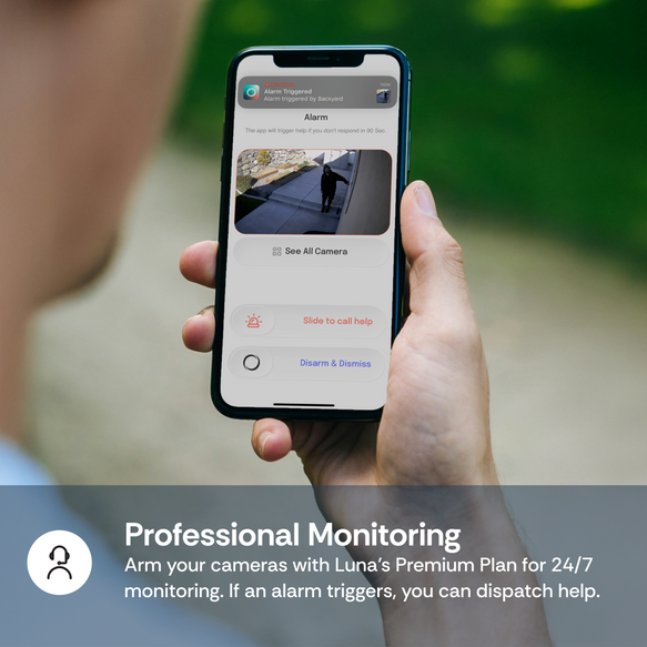 Person holding a smartphone with a security app on a blurred outdoor background